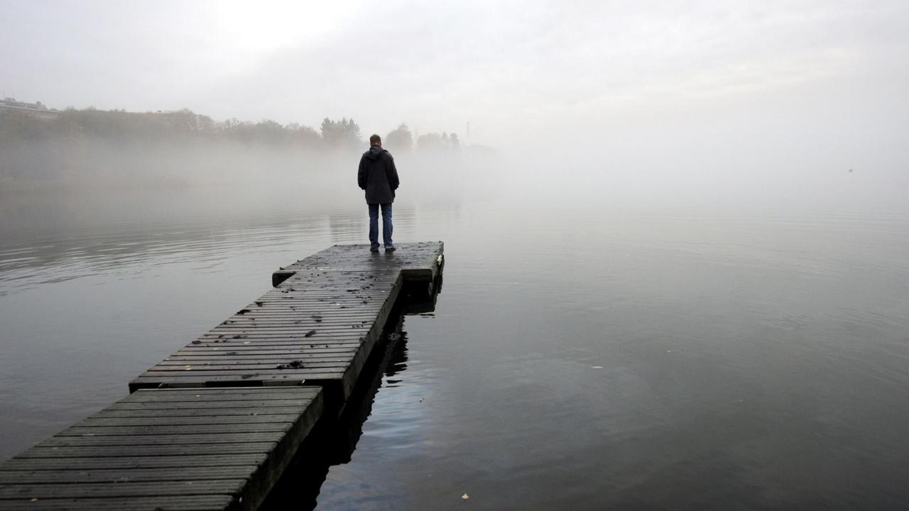 Ein einsamer Mann an der Töölönlahti Bucht in Helsinki Ein einsamer Mann an der Töölönlahti Bucht in Helsinki