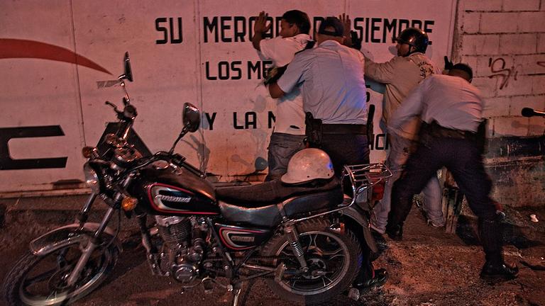 Polizisten durchsuchen in Caracas Jugendliche nach Waffen. Polizisten durchsuchen in Caracas Jugendliche nach Waffen.