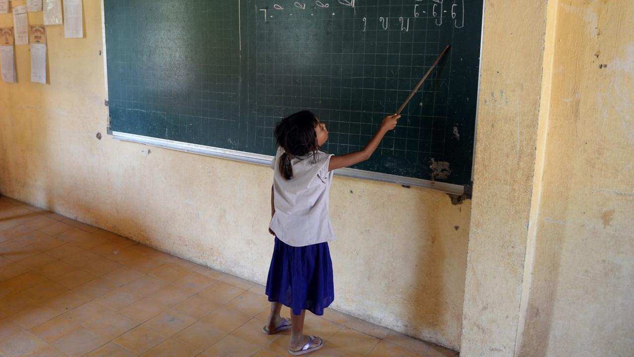 Eine Schülerin steht am 11.10.2013 in Phnom Penh (Kambodscha) in der Kdei Chas Primary School an der Tafel und zeigt mit einem Zeigestock auf Buchstaben in Khmer-Schrift. Eine Schülerin steht am 11.10.2013 in Phnom Penh (Kambodscha) in der Kdei Chas Primary School an der Tafel und zeigt mit einem Zeigestock auf Buchstaben in Khmer-Schrift.