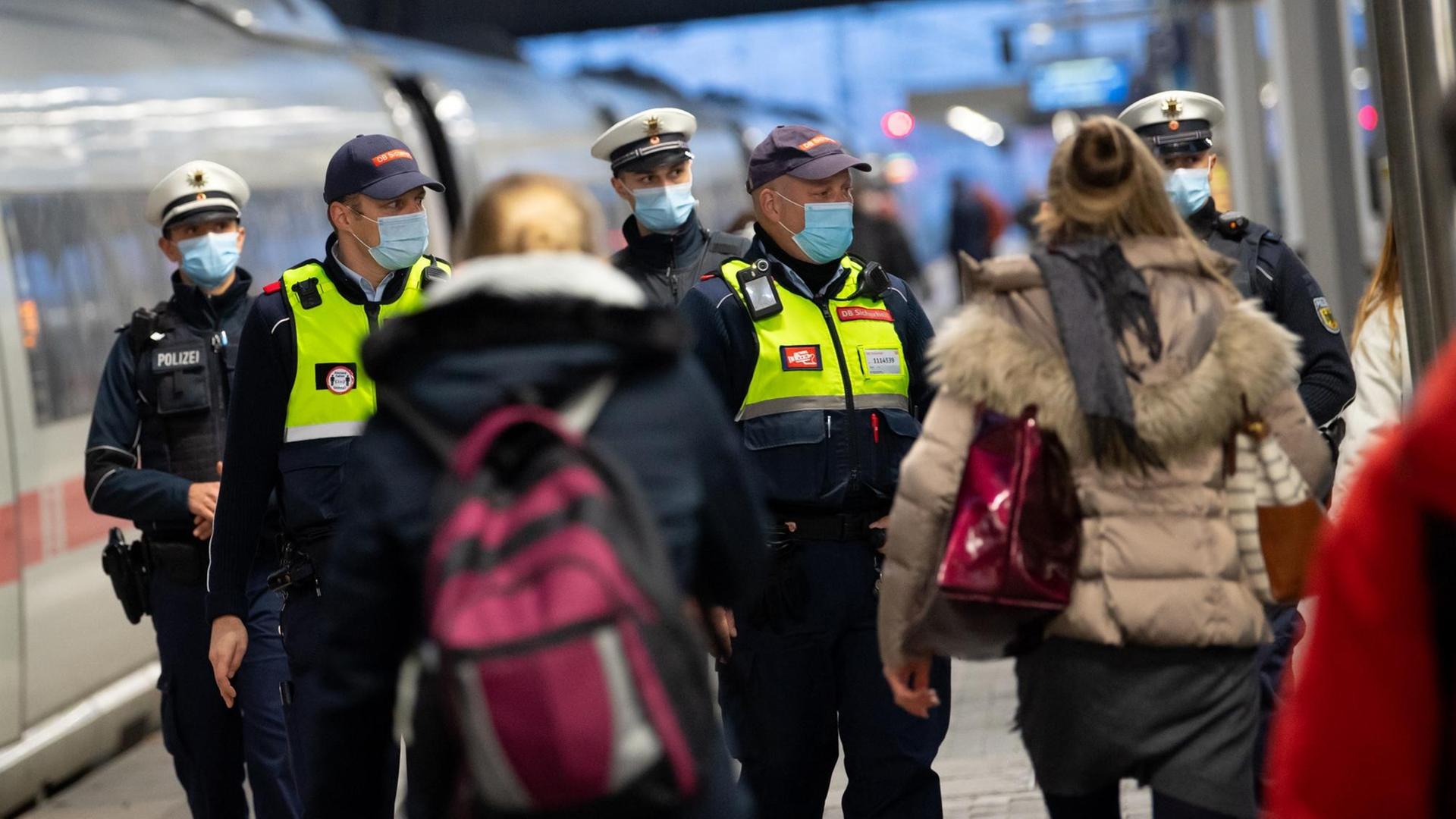 Sicherheitsmitarbeiter der Deutsche Bahn kontrollieren zusammen mit Polizisten der Bundespolizei die Einhaltung der Maskenpflicht am Hauptbahnhof in München. Sicherheitsmitarbeiter der Deutsche Bahn kontrollieren zusammen mit Polizisten der Bundespolizei die Einhaltung der Maskenpflicht am Hauptbahnhof in München.