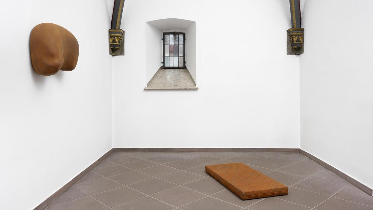 Eine rostbraun eingefärbte Matratze liegt in einem Raum - Kunstwerke von Thomas Rentmeister