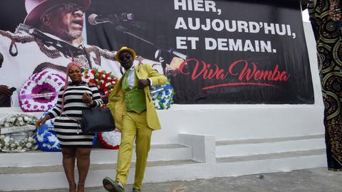 Besucher des Femua Festivals in Abidjan (Elfenbeinküste) posieren vor einem Plakat, dass an den verstorbenen kongolesischen Popstar Papa Wembe erinnert.