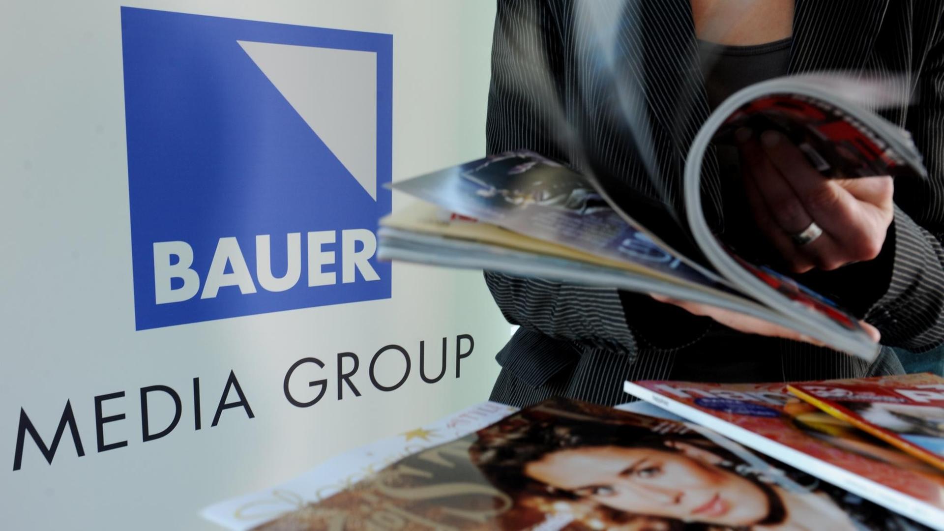 Eine Frau blättert auf der Jahrespressekonferenz der Bauer Media Group in Hamburg vor dem Firmenlogo in einer Zeitschrift. Eine Frau blättert auf der Jahrespressekonferenz der Bauer Media Group in Hamburg vor dem Firmenlogo in einer Zeitschrift.