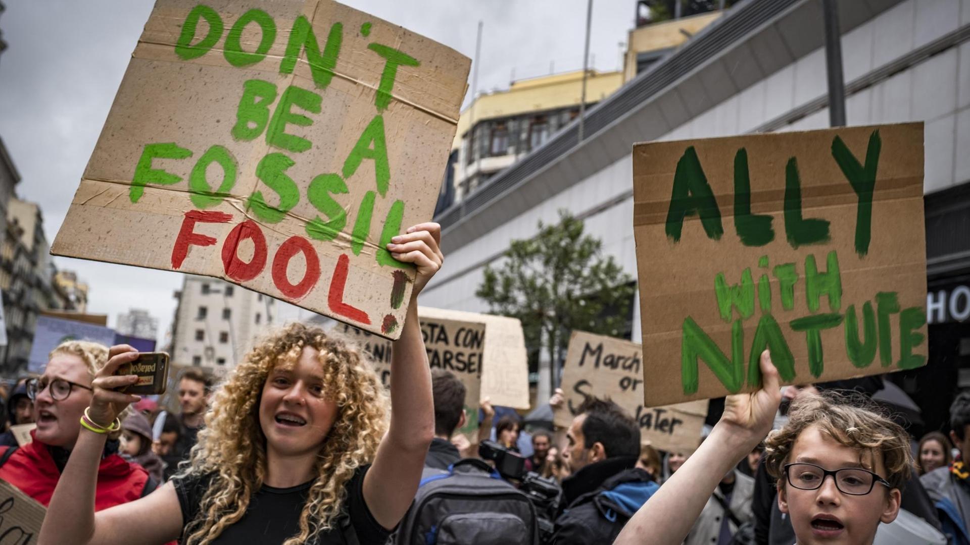 Jugendliche DemonstrantInnen die ein Schild mit der Aufschrift "Don't be a fossil - Fool!" hochhalten. Jugendliche DemonstrantInnen die ein Schild mit der Aufschrift "Don't be a fossil - Fool!" hochhalten.