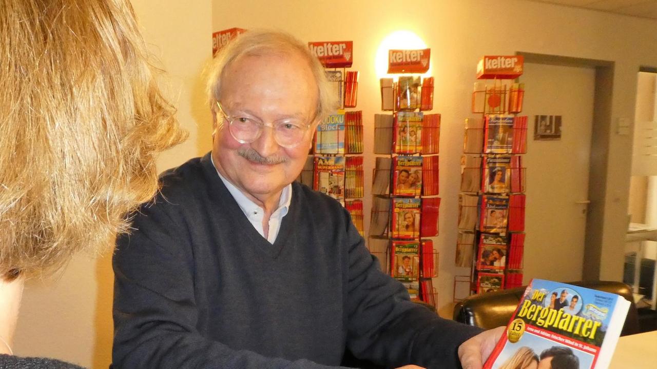 Gerhard Melchert vor Heftromanen und Der Bergdoktor in der Hand
