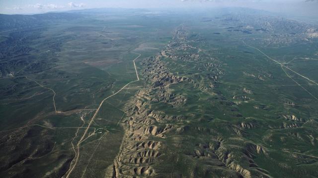 Luftaufnahme der Carrizo-Ebene in Kalifornien. In der Mitte ist deutlich zu erkennen, wie die Gesteinsschichten entlang einer geraden Linie verzerrt werden: Die San Andreas Verwerfung.