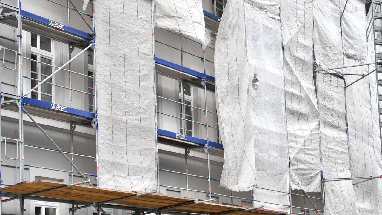 Ein Haus in München ist eingerüstet, am Gerüst hängen Planen und verdecken die Fassade zum Teil. Ein Haus in München ist eingerüstet, am Gerüst hängen Planen und verdecken die Fassade zum Teil.