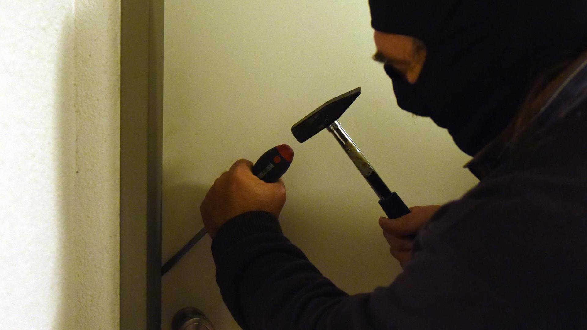 ILLUSTRATION - Ein Mann versucht am 29.10.2015 in Freiburg (Baden-Württemberg) mit einem Hammer und einem Schraubenzieher bei einem Einbruch eine Wohnungstür aufzuhebeln. ILLUSTRATION - Ein Mann versucht am 29.10.2015 in Freiburg (Baden-Württemberg) mit einem Hammer und einem Schraubenzieher bei einem Einbruch eine Wohnungstür aufzuhebeln.