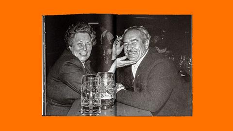 Das Bild zeigt eine Doppelseite aus einem Fotoband: Ein älteres Paar sitzt mit Biergläsern an einem Biertisch. Die Frau streicht dem Mann übers Kinn.