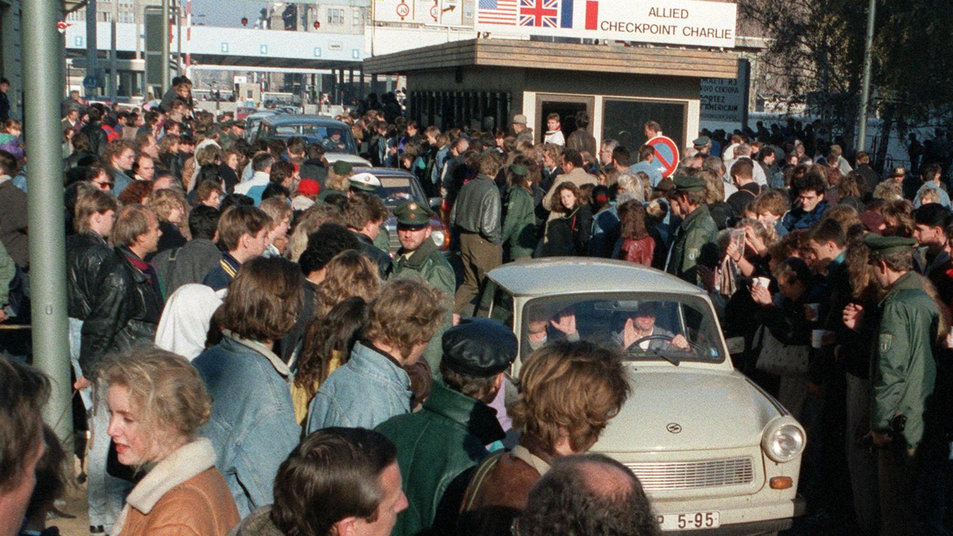 Trabis fahren am 10.11.1989 durch eine jubelnde Menschenmenge am Checkpoint Charlie file_source: picture-alliance / dpa