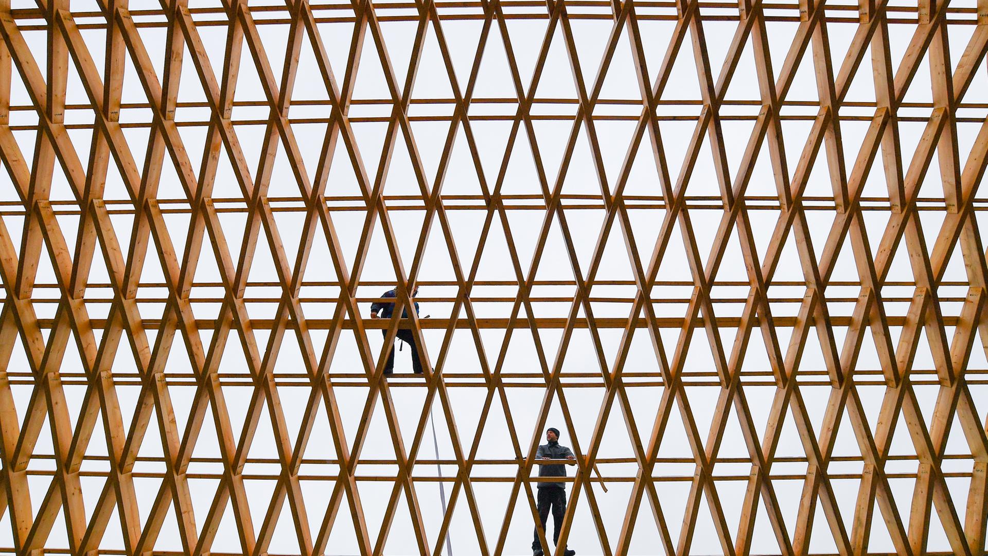 Zwei Mitarbeiter der Firma Elite Holzbau an der Dachkonstruktion einer Werkhalle Zwei Mitarbeiter der Firma Elite Holzbau an der Dachkonstruktion einer Werkhalle