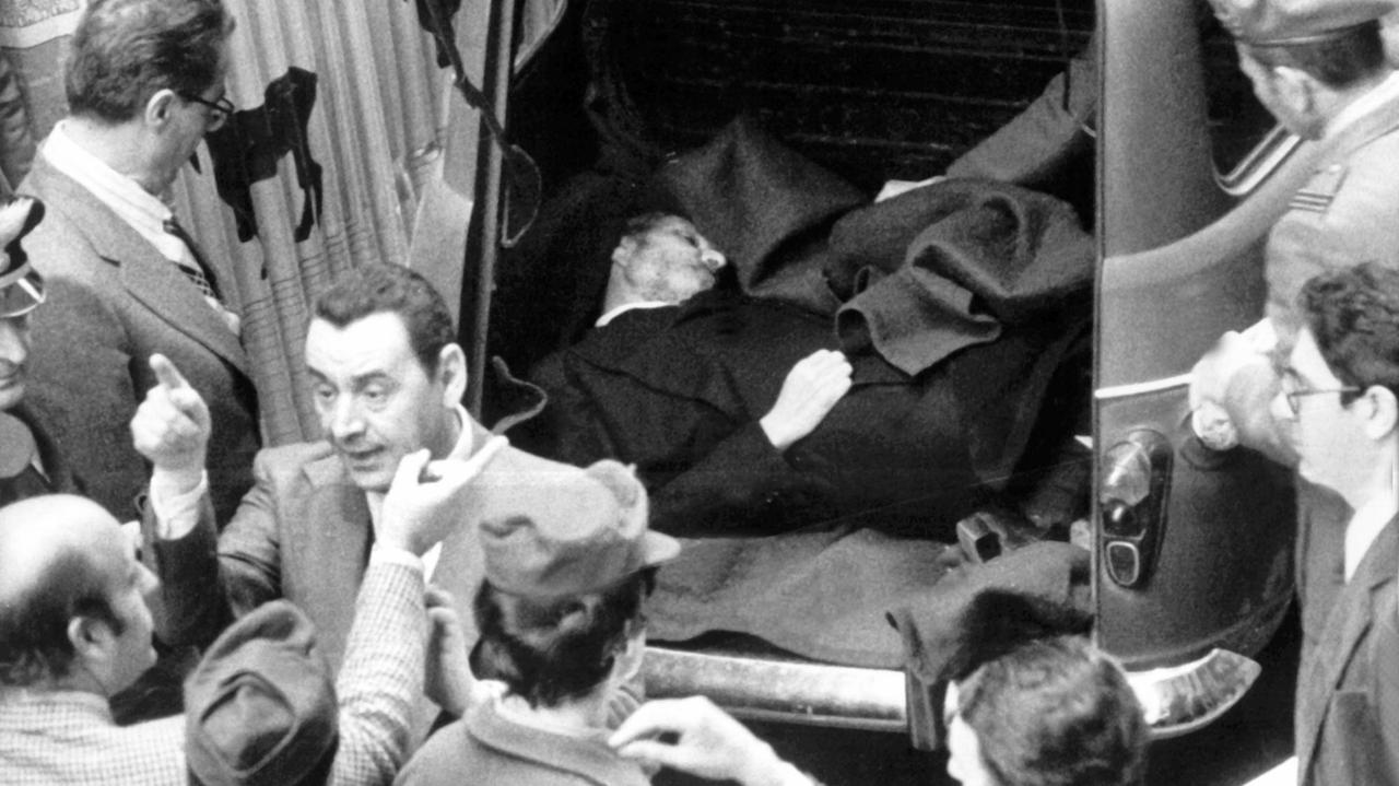 Eine historische schwarz/weiss Aufnahme von der Leiche Aldo Moros, die in einem Kofferraum liegt, mit Polizisten und aufgeregt diskutierenden Menschen drumherum. 55 Tage nach seiner Entführung ist der italienische Politiker Aldo Moro am 9. Mai 1978 im Zentrum Roms in einem Auto ermordet aufgefunden worden. Eine historische schwarz/weiss Aufnahme von der Leiche Aldo Moros, die in einem Kofferraum liegt, mit Polizisten und aufgeregt diskutierenden Menschen drumherum. 55 Tage nach seiner Entführung ist der italienische Politiker Aldo Moro am 9. Mai 1978 im Zentrum Roms in einem Auto ermordet aufgefunden worden.