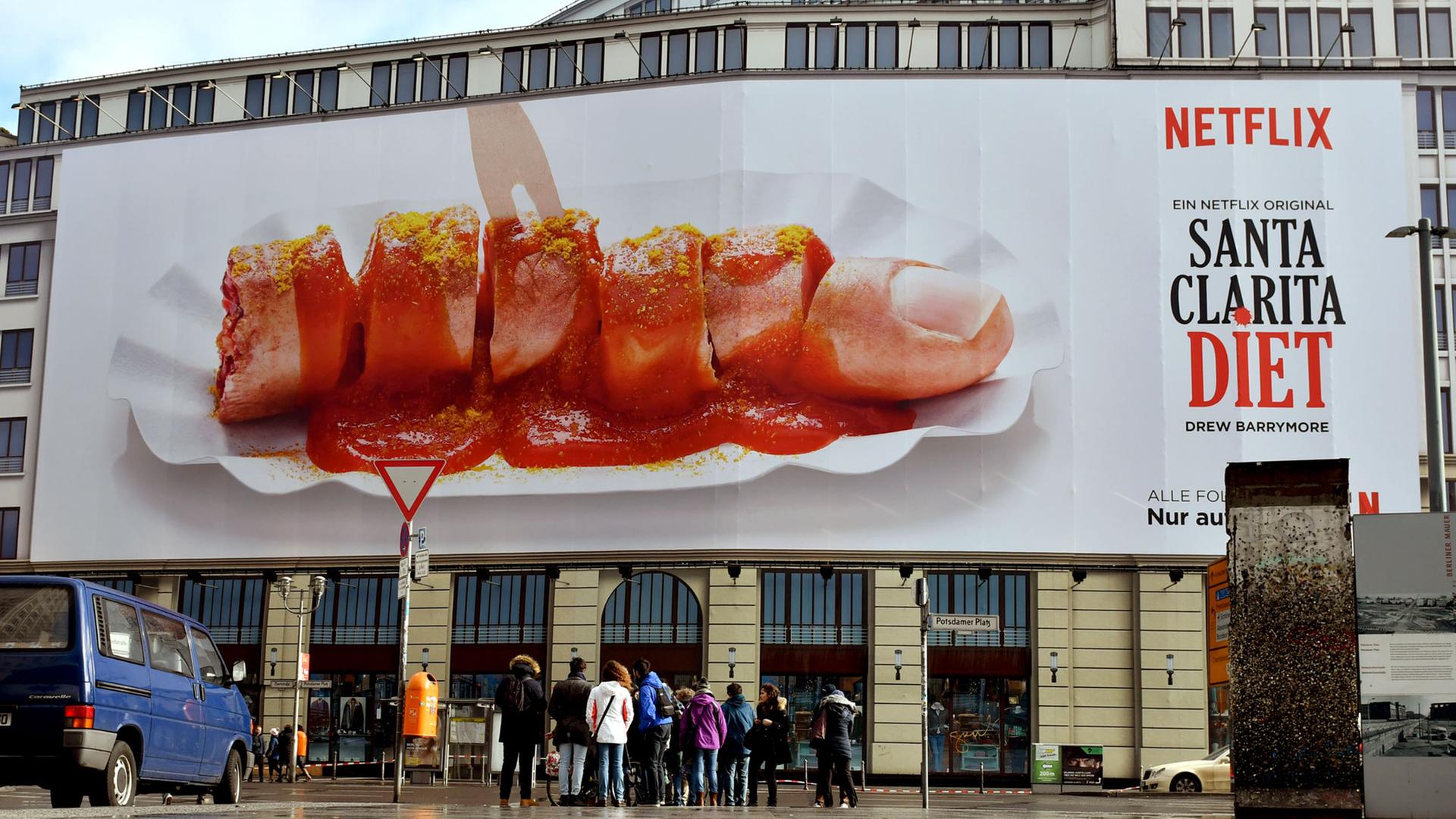 Ein zerstückelter Finger in Form einer Curry-Wurst ist am 21.02.2017 in Berlin auf dem Werbeplakat des US-amerikanischen Unternehmens Netflix am Potsdamer Platz zu sehen. Damit macht der Streamingdienst Werbung für seine neue Zombie-Serie "Santa Clarita Diet". Die unterschiedlichen Plakate stoßen allerdings nicht überall auf Begeisterung. Aufgrund einiger Beschwerden beim Werberat hat Netflix einige Banner wieder abgehängt. Ein zerstückelter Finger in Form einer Curry-Wurst ist am 21.02.2017 in Berlin auf dem Werbeplakat des US-amerikanischen Unternehmens Netflix am Potsdamer Platz zu sehen. Damit macht der Streamingdienst Werbung für seine neue Zombie-Serie "Santa Clarita Diet". Die unterschiedlichen Plakate stoßen allerdings nicht überall auf Begeisterung. Aufgrund einiger Beschwerden beim Werberat hat Netflix einige Banner wieder abgehängt.