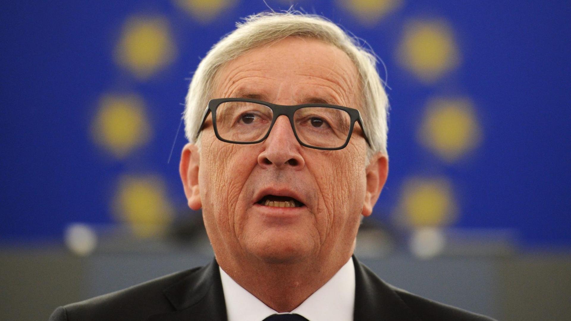 Juncker ist so fotografiert, dass sein Kopf von den europäischen Sternen umrahmt zu sein scheint, die auf einem blauen Banner hinter ihm zu sehen sind.