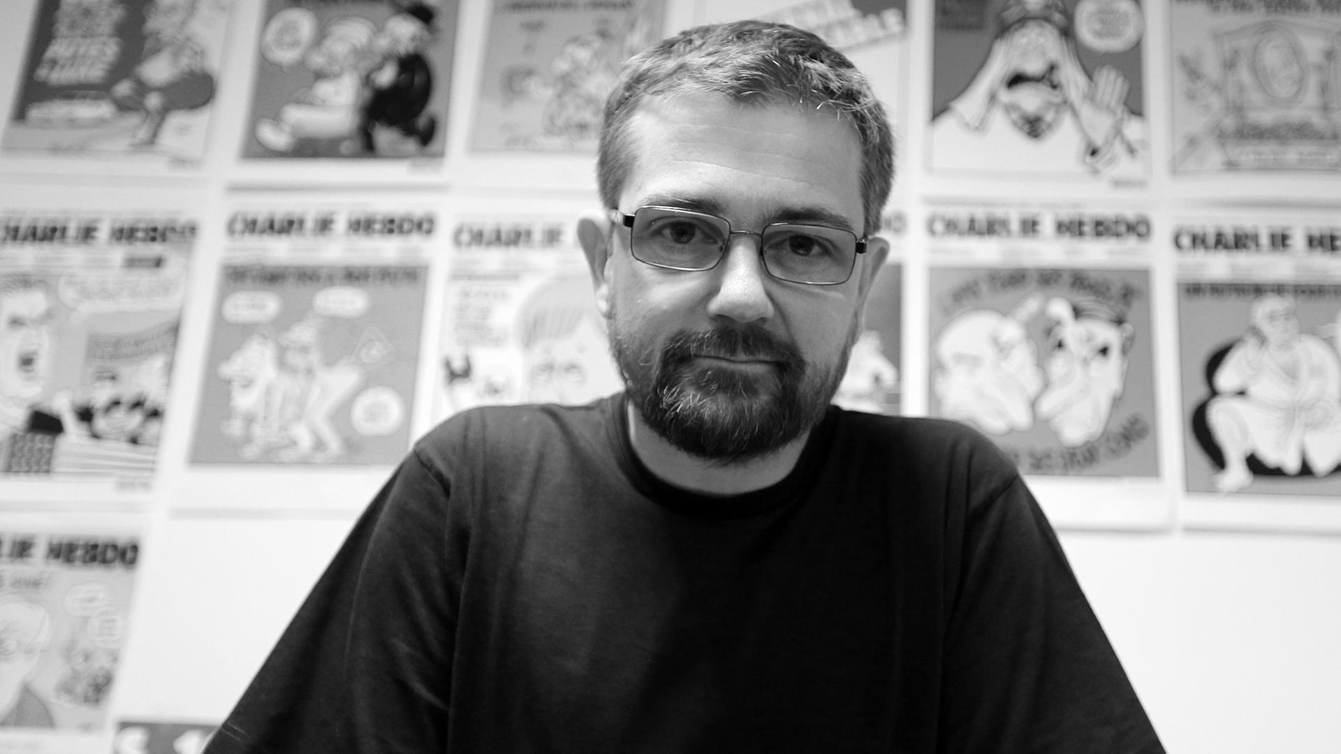 Der Karikaturist und Journalist Stéphane Charbonnier, genannt "Charb", vor einer Auswahl von Karikaturen.