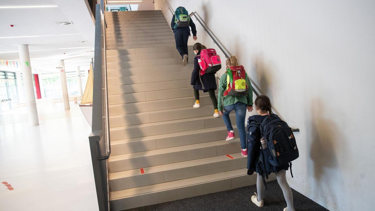 In einer Hamburger Grundschule gehen mit Abstand Schüler und Schülerinnen eine Treppe hinauf.  