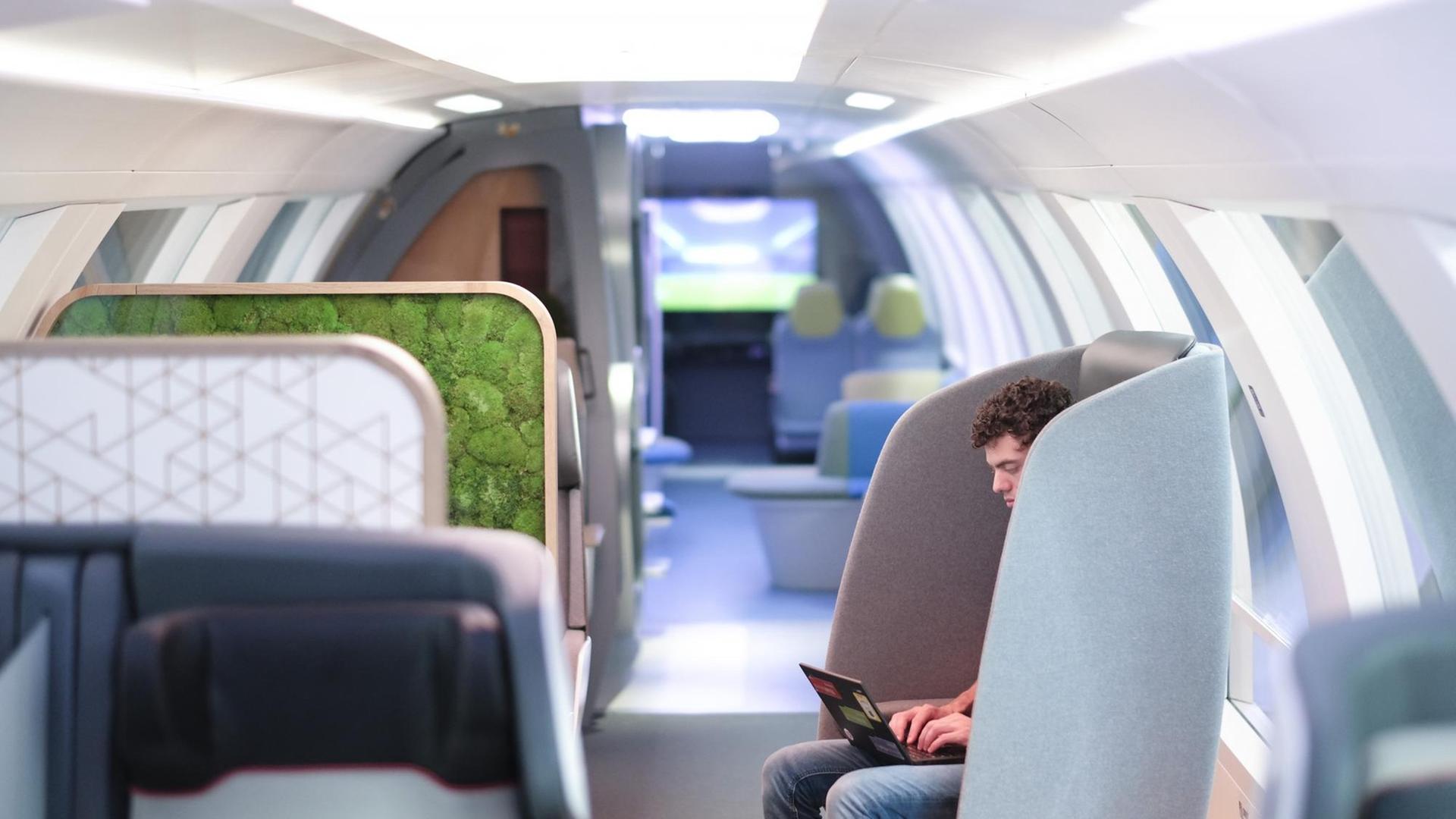 Ein jungen Mann sitzt, mit einem Laptop auf dem Schoß, im Sessel des innovation "Ideenzugs" der Deutschan Bahn. Ein jungen Mann sitzt, mit einem Laptop auf dem Schoß, im Sessel des innovation "Ideenzugs" der Deutschan Bahn.