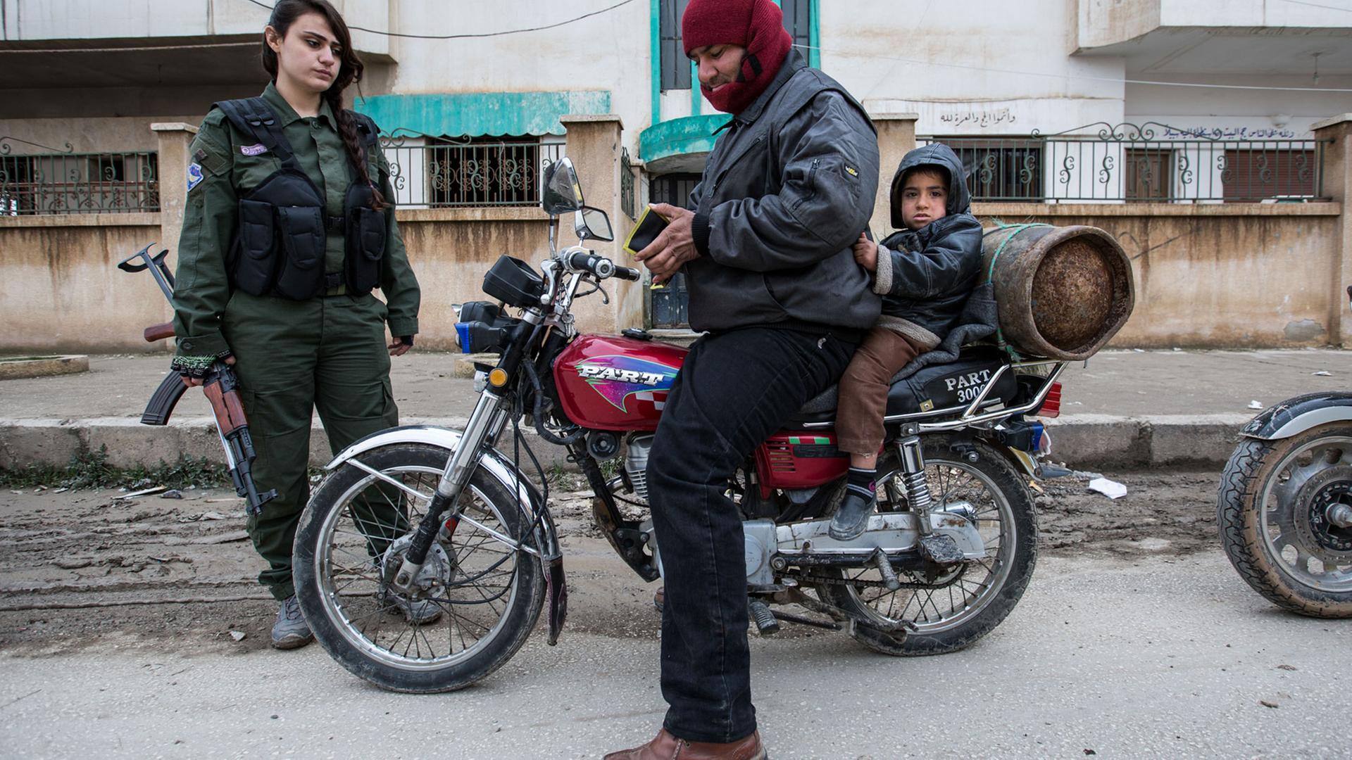 Eine Kämpferin der Christlichen Frauenmiliz kontrolliert die Papiere eines Motorradfahrers. Eine Kämpferin der Christlichen Frauenmiliz kontrolliert die Papiere eines Motorradfahrers.