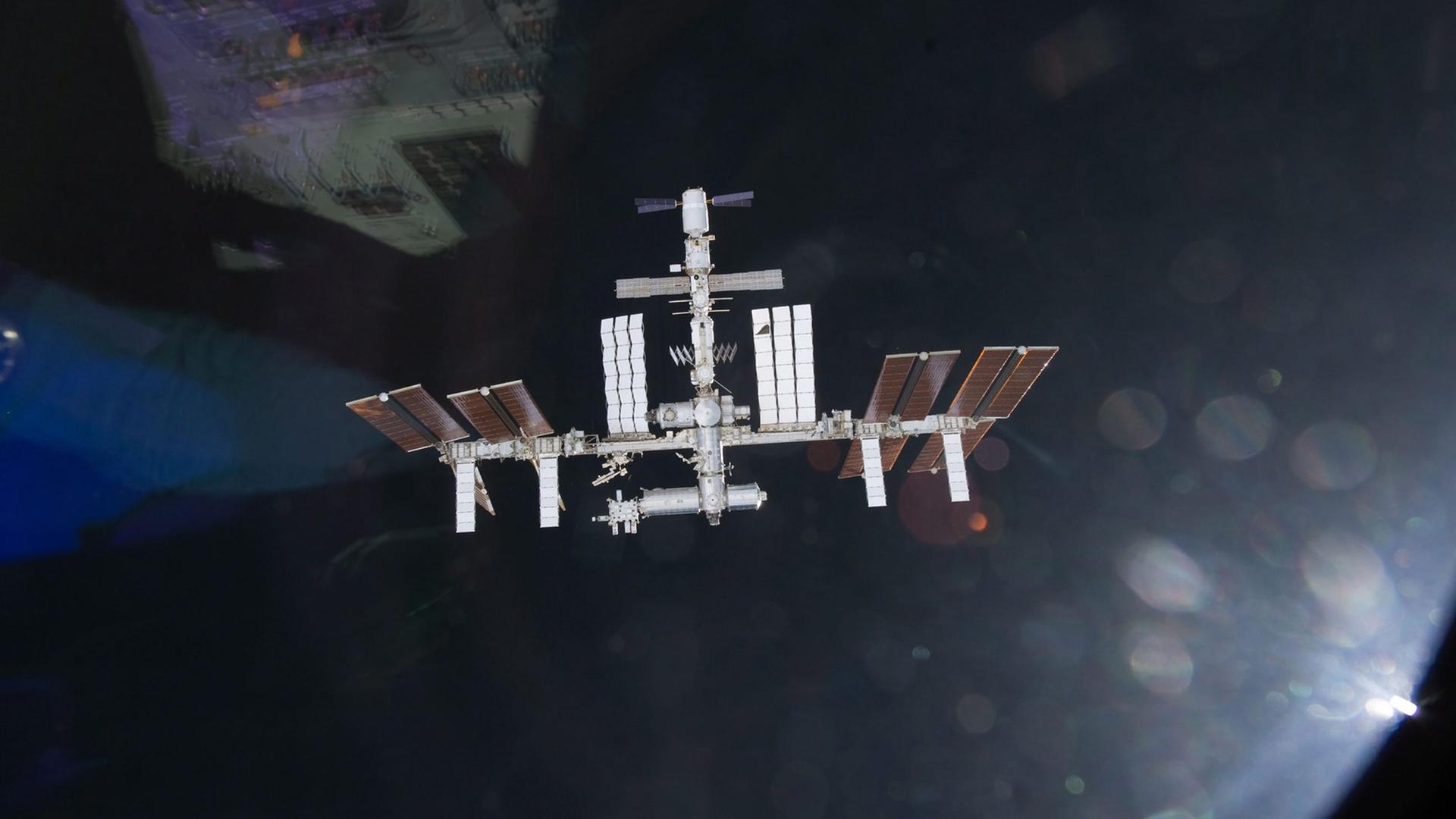 Internationale Raumstation ISS fliegt im Weltall. Im Hintergrund die Erdkugel Internationale Raumstation ISS fliegt im Weltall. Im Hintergrund die Erdkugel