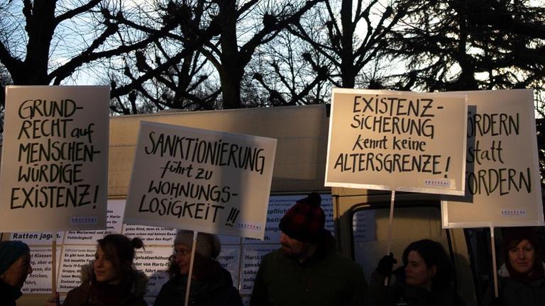 Demonstranten stehen während der mündlichen Verhandlung über die Rechtmäßigkeit von Hartz-IV-Sanktionen vor dem Bundesverfassungsgericht. Das Sozialgericht Gotha hält die Praxis, nach der Hartz-IV-Empfängern Leistungskürzungen drohen, wenn sie ihren Pflichten nicht nachkommen, für verfassungswidrig. Daher hat es einen Fall in Karlsruhe vorgelegt. Das Urteil wird in der Regel einige Monate nach der Verhandlung verkündet. Demonstranten stehen während der mündlichen Verhandlung über die Rechtmäßigkeit von Hartz-IV-Sanktionen vor dem Bundesverfassungsgericht. Das Sozialgericht Gotha hält die Praxis, nach der Hartz-IV-Empfängern Leistungskürzungen drohen, wenn sie ihren Pflichten nicht nachkommen, für verfassungswidrig. Daher hat es einen Fall in Karlsruhe vorgelegt. Das Urteil wird in der Regel einige Monate nach der Verhandlung verkündet.