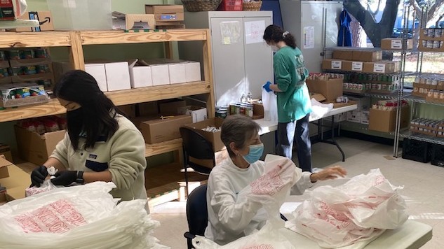 Drei Frauen in einem Raum befüllen Plastiktüten mit Lebensmitteln. Drei Frauen in einem Raum befüllen Plastiktüten mit Lebensmitteln.