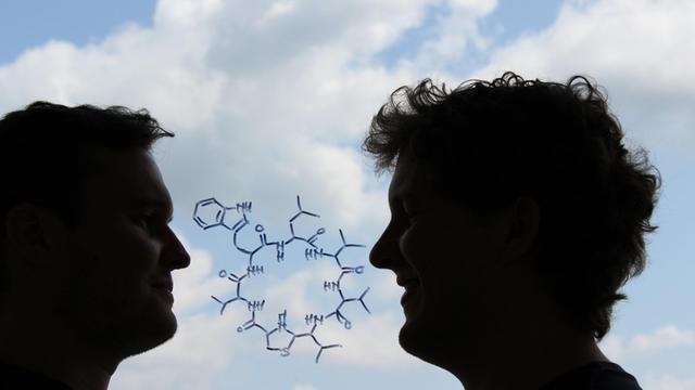 Die chemische Strukturformel des neu entdeckten Antibiotikums "Lugdunin". Außerdem im Bild: die beiden Erstautoren Alexander Zipperer (links) und Martin Christoph Konnerth (rechts).