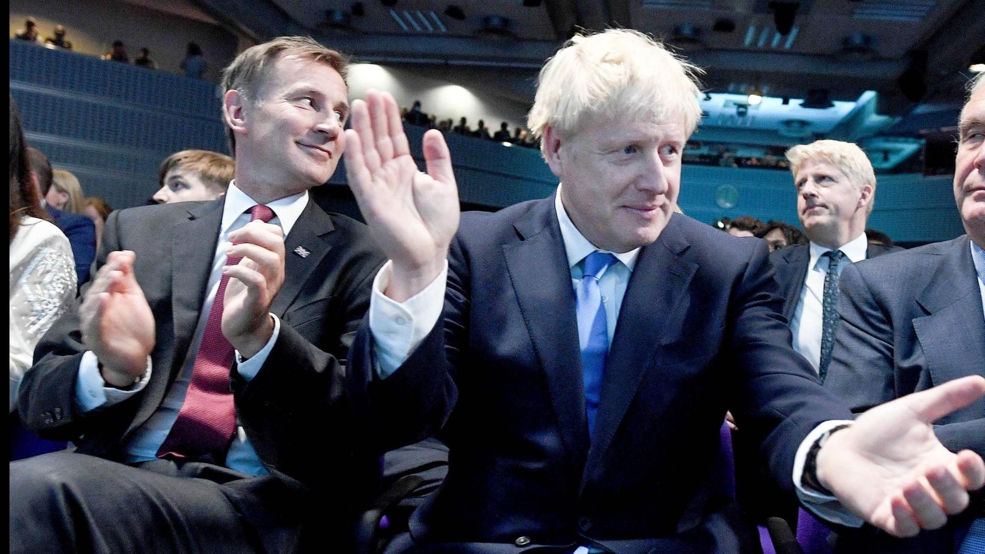 Boris Johnson (Mitte) und Jeremy Hunt klatschen bei der Verkündung des neuen Tory-Chefs.