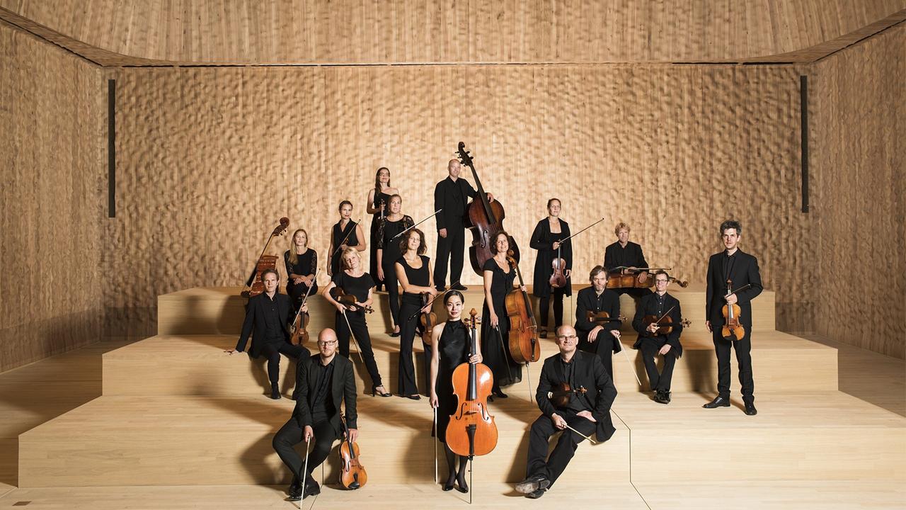 Rund 20 Menschen stehen mit ihren Instrumenten in einem hellbraunen Raum, es ist der kleine Saal der Elbphilharmonie in Hamburg. Rund 20 Menschen stehen mit ihren Instrumenten in einem hellbraunen Raum, es ist der kleine Saal der Elbphilharmonie in Hamburg.