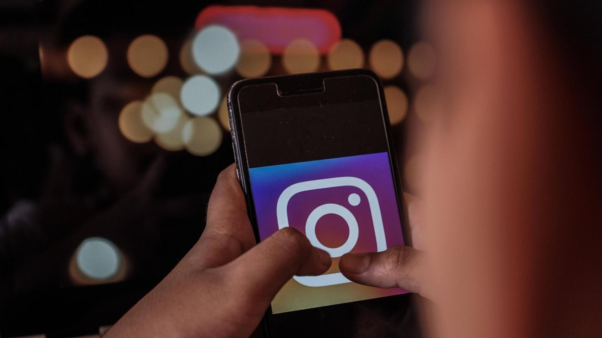 Eine Hand hält ein Smartphone, auf dessen Display das Instagram-Logo zu sehen ist. Eine Hand hält ein Smartphone, auf dessen Display das Instagram-Logo zu sehen ist.