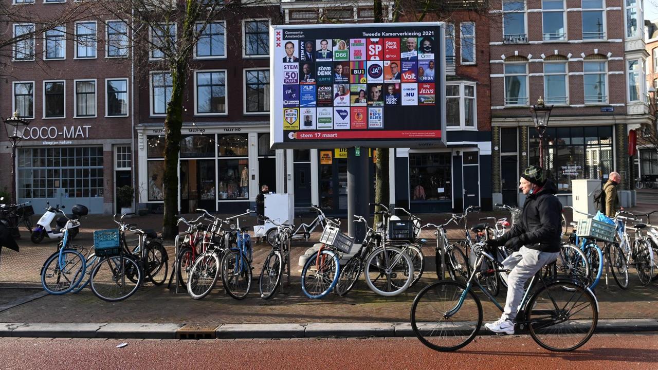 Ein Radfahrer fährt in Amsterdam an einem Ständer mit den Plakaten aller an den niederländischen Parlamentswahlen teilnehmenden Parteien vorbei.