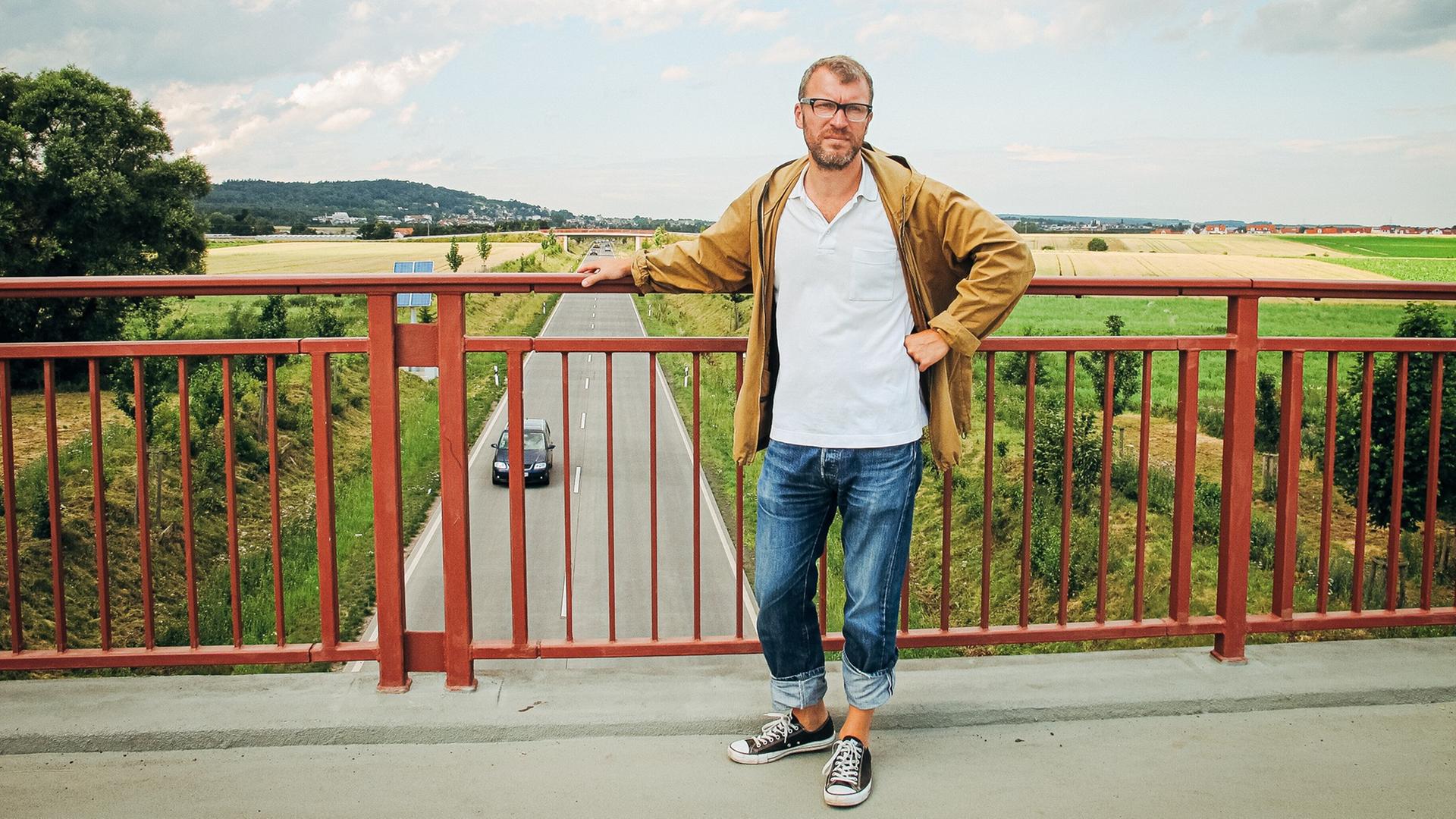 Andreas Maier steht in der Wetterau auf einer Brücke, auf der man die B3 überqueren kann (Foto vom 10.07.2012). Mit der B3 kann man sich auch literarisch auseinandersetzen - das tut der aus der Wetterau stammende Schriftsteller Andreas Maier. Für ihn ist die Straße ein Symbol für die Zerstörung seiner Heimat geworden. Andreas Maier steht in der Wetterau auf einer Brücke, auf der man die B3 überqueren kann (Foto vom 10.07.2012). Mit der B3 kann man sich auch literarisch auseinandersetzen - das tut der aus der Wetterau stammende Schriftsteller Andreas Maier. Für ihn ist die Straße ein Symbol für die Zerstörung seiner Heimat geworden.