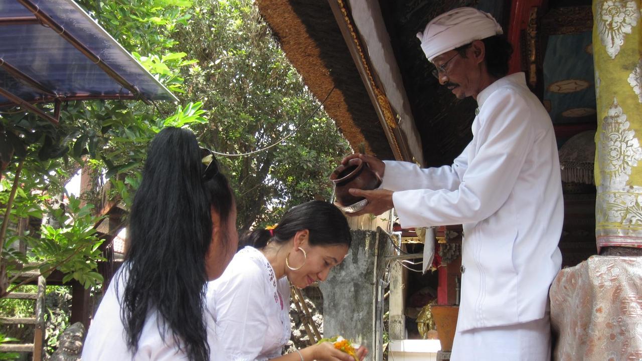 Der Brahmanenpriester Ida Bagus Alit segnet Geschäftsfrauen, die extra aus Java gekommen sind, mit heiligem Wasser. Der Brahmanenpriester Ida Bagus Alit segnet Geschäftsfrauen, die extra aus Java gekommen sind, mit heiligem Wasser.