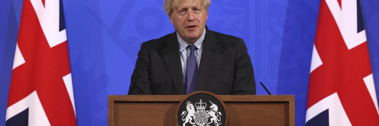 Großbritanniens Premier Boris Johnson steht neben Flaggen am rednerpult und informiert über die Corona-Maßnahmen. Großbritanniens Premier Boris Johnson steht neben Flaggen am rednerpult und informiert über die Corona-Maßnahmen.