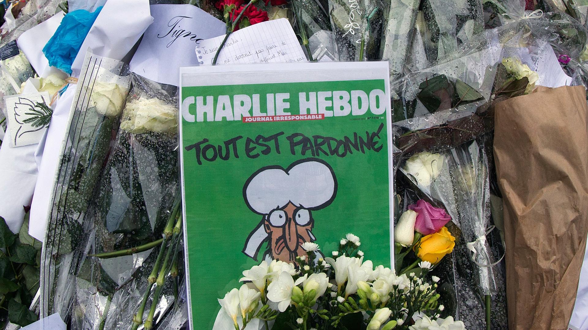 Blumen und die aktuelle "Charlie Hebdo"-Ausgabe vor der Redaktion des Satiremagazins