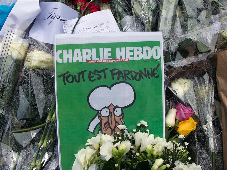 Blumen und die aktuelle "Charlie Hebdo"-Ausgabe vor der Redaktion des Satiremagazins