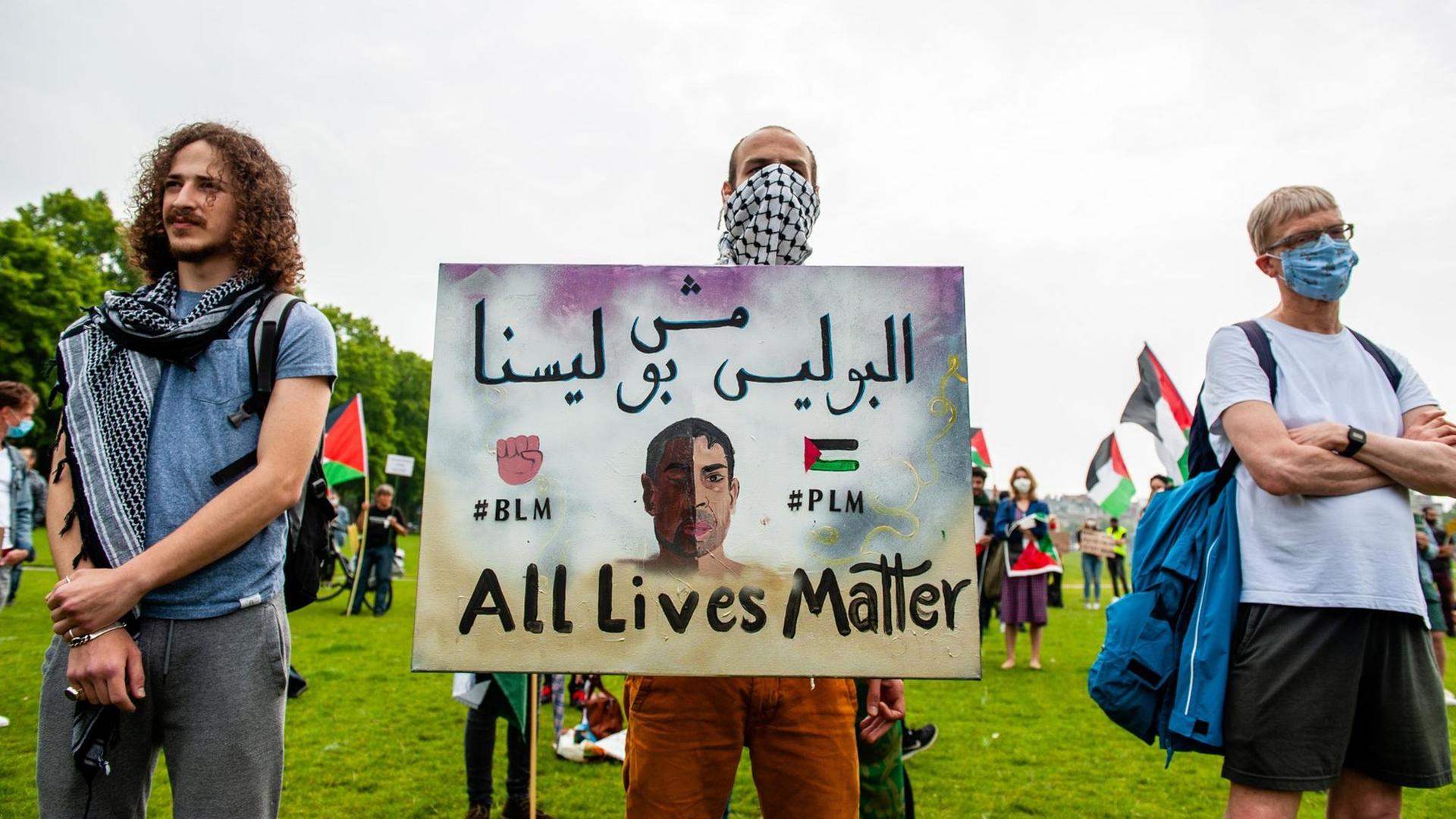 Ein Demonstrant hält ein Schild mit der Aufschrift: "#BLM #PLM All Lives Matter".