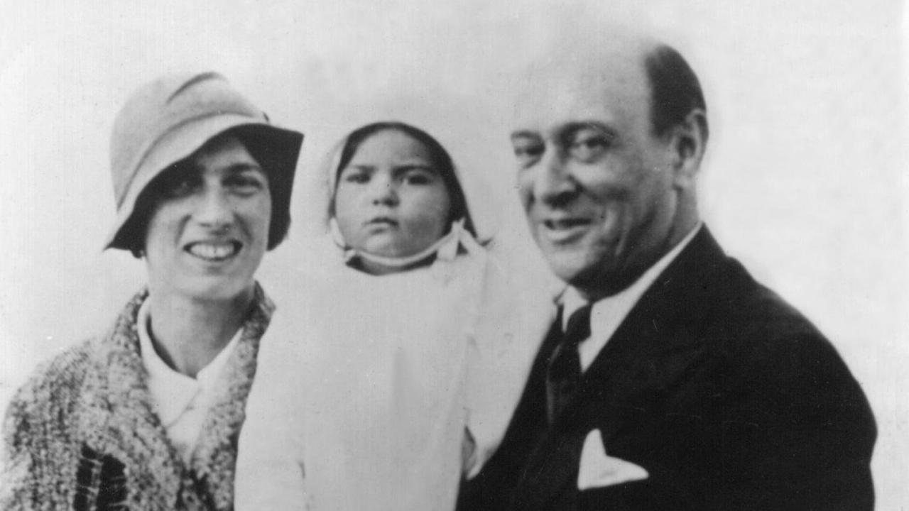 Eine historische Fotografie zeigt einen Mann mit Frau und Kind glücklich in die Kamera lächelnd.