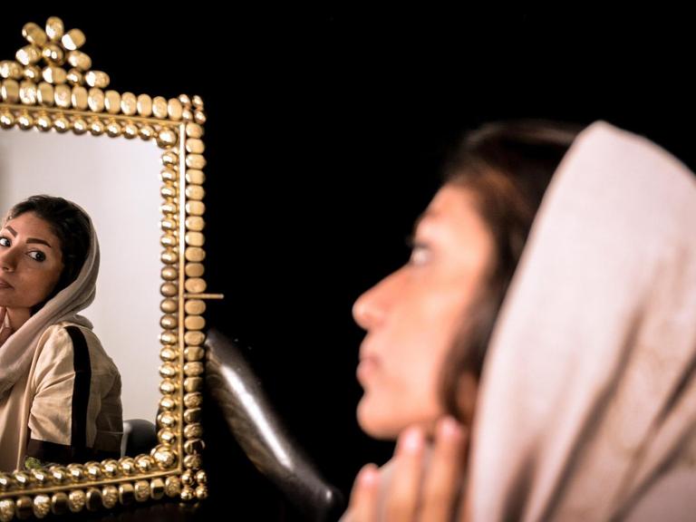 Eine junge Iranerin betrachtet ihr Spiegelbild, während sie auf eine Voruntersuchung für einen plastischen Eingriff wartet.