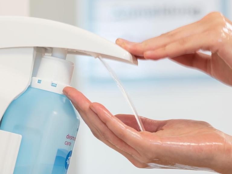 Eine Mitarbeiterin desinfiziert sich die Hände in einem Medizinischen Versorgungszentrum in einer Klinik.