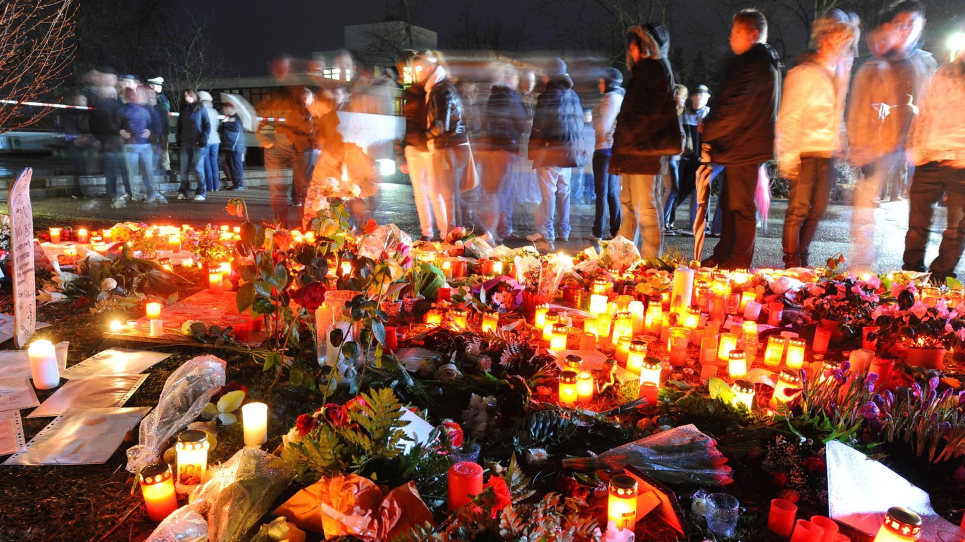 Das Bild zeigt Blumen, Grablichter und trauernde Menschen einen Tag nach dem Amoklauf von Winnenden.
