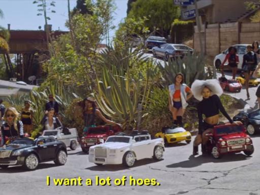 Screenshot einer Szene aus dem Video "Wyclef Jean" von Young Thug, in dem junge Frauen auf Kinderspielzeugautos sitzen. https://www.youtube.com/watch?v=_9L3j-lVLwk