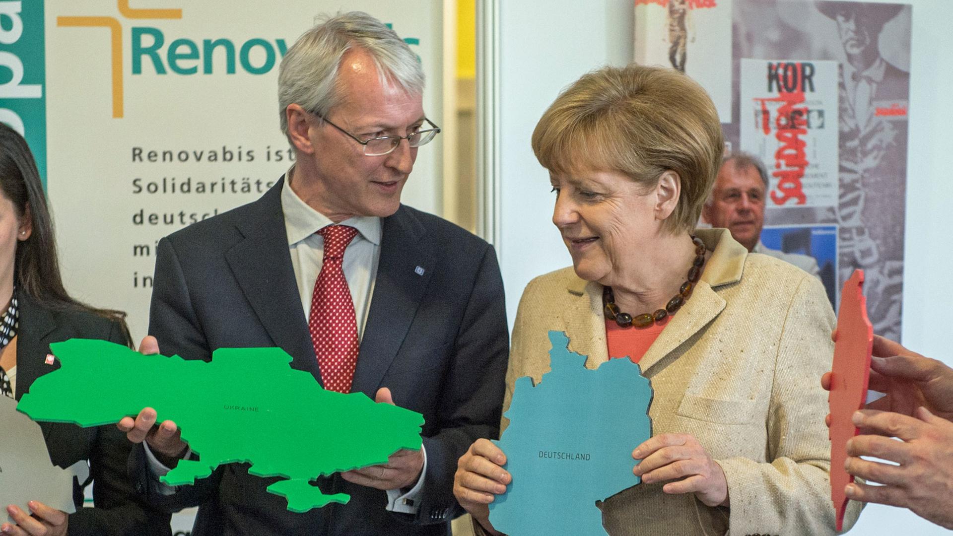Bundeskanzlerin Angela Merkel (CDU) hält am 30.05.2014 beim Katholikentag in Regensburg (Bayern) auf einem Informationsstand des Osteuropa-Hilfswerks Renovabis einen Karton mit dem Umriss von Deutschland, daneben Andrij Waskowycz, Direktor der griechisch-katholischen Caritas der Ukraine, der einen Karton mit dem Umriss der Ukraine in Händen hält. Bis zum 1. Juni findet in der Domstadt der 99. Deutsche Katholikentag statt. Bundeskanzlerin Angela Merkel (CDU) hält am 30.05.2014 beim Katholikentag in Regensburg (Bayern) auf einem Informationsstand des Osteuropa-Hilfswerks Renovabis einen Karton mit dem Umriss von Deutschland, daneben Andrij Waskowycz, Direktor der griechisch-katholischen Caritas der Ukraine, der einen Karton mit dem Umriss der Ukraine in Händen hält. Bis zum 1. Juni findet in der Domstadt der 99. Deutsche Katholikentag statt.