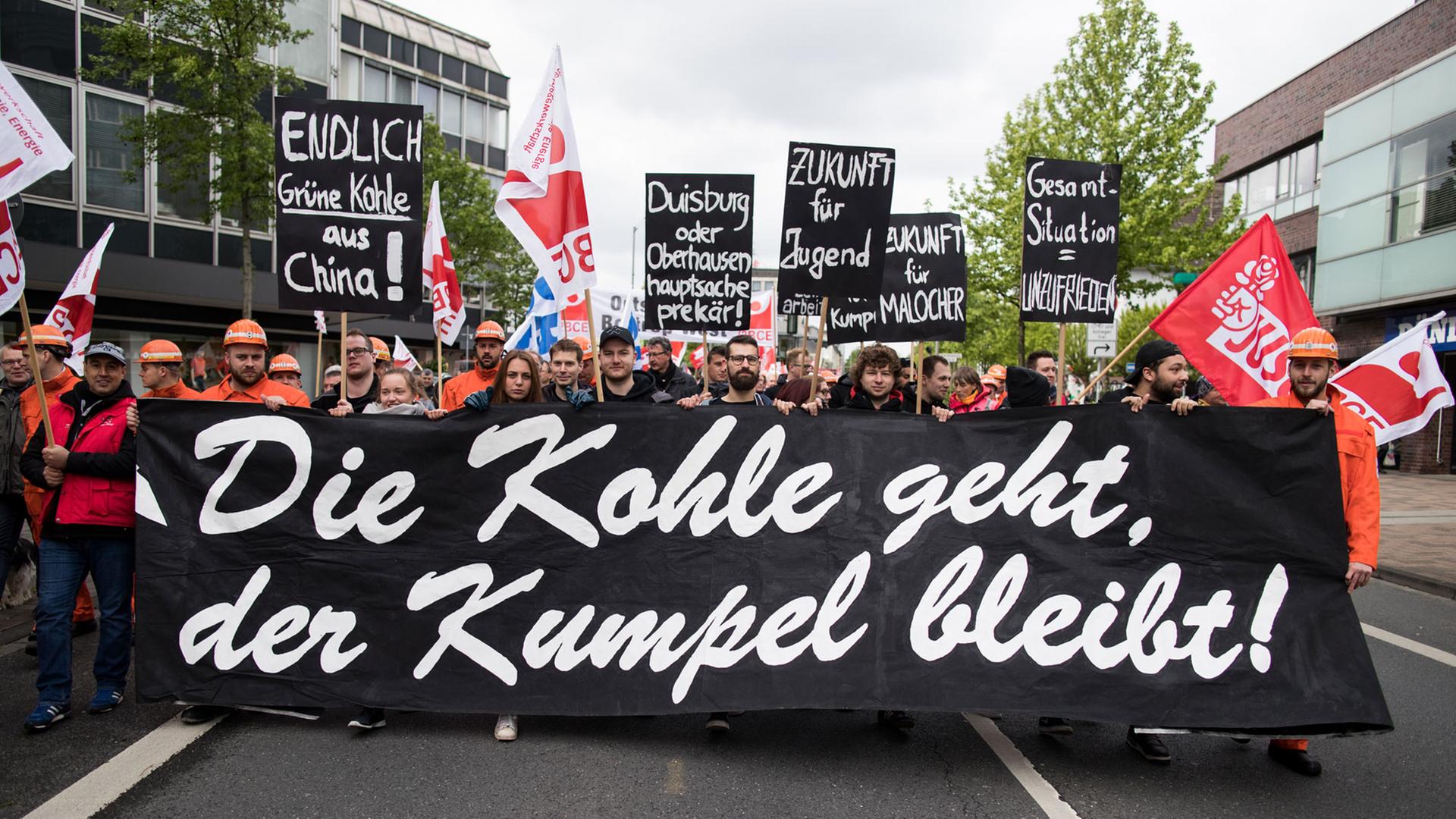 "Die Kohle geht, der Kumpel bleibt" steht mit weißer Schrift auf einem schwarzen Banner während eines Demonstrationszuges in Bottrop am 1. Mai 2018 "Die Kohle geht, der Kumpel bleibt" steht mit weißer Schrift auf einem schwarzen Banner während eines Demonstrationszuges in Bottrop am 1. Mai 2018