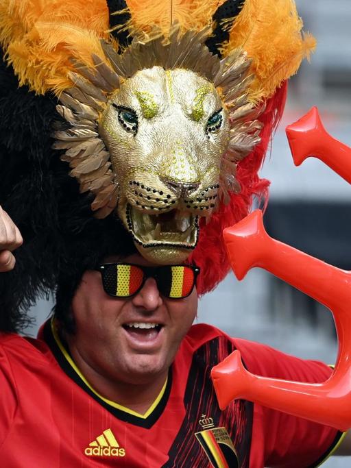 Ein Fan bei der Fußball-EM mit Sonnenbrille in belgischen Landesfarben, Löwenkopfschmuck und Aufblas-Dreizack.