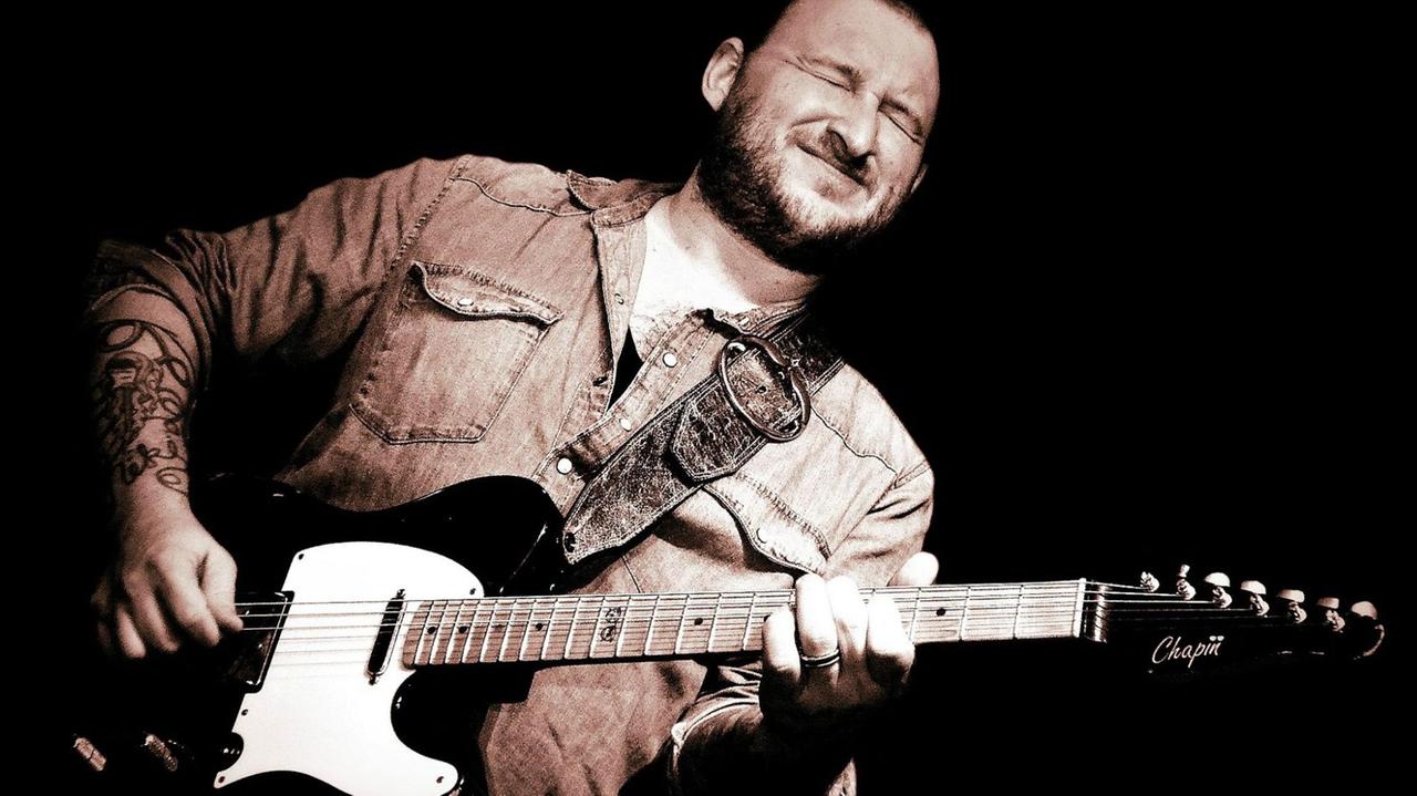 Ein mit einer schwarz-weißen Telecaster-Gitarre steht mit geschlossenen Augen auf einer Bühne, Ein mit einer schwarz-weißen Telecaster-Gitarre steht mit geschlossenen Augen auf einer Bühne,
