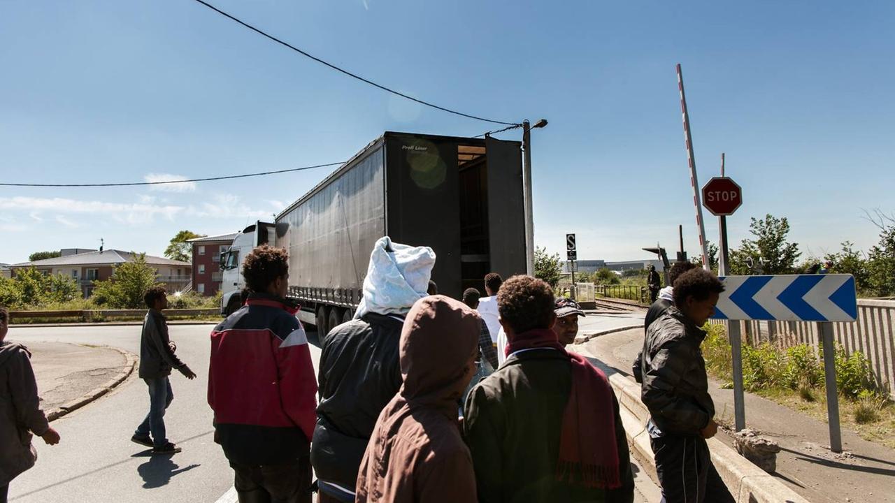 Flüchtlinge und ein Laster auf einer Straße in Calais Flüchtlinge und ein Laster auf einer Straße in Calais