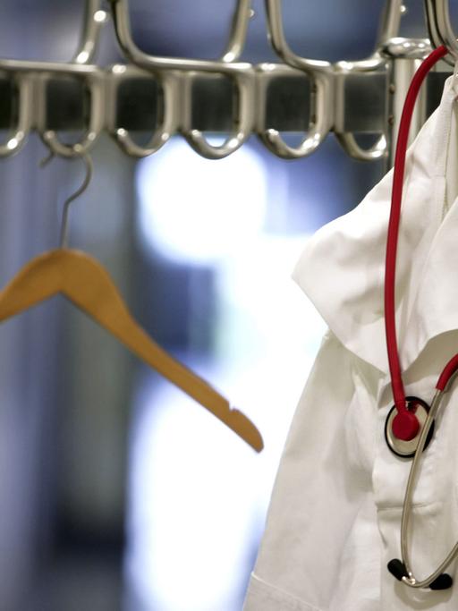 Ein Arztkittel und Stethoskop hängt an einer Garderobenständer.