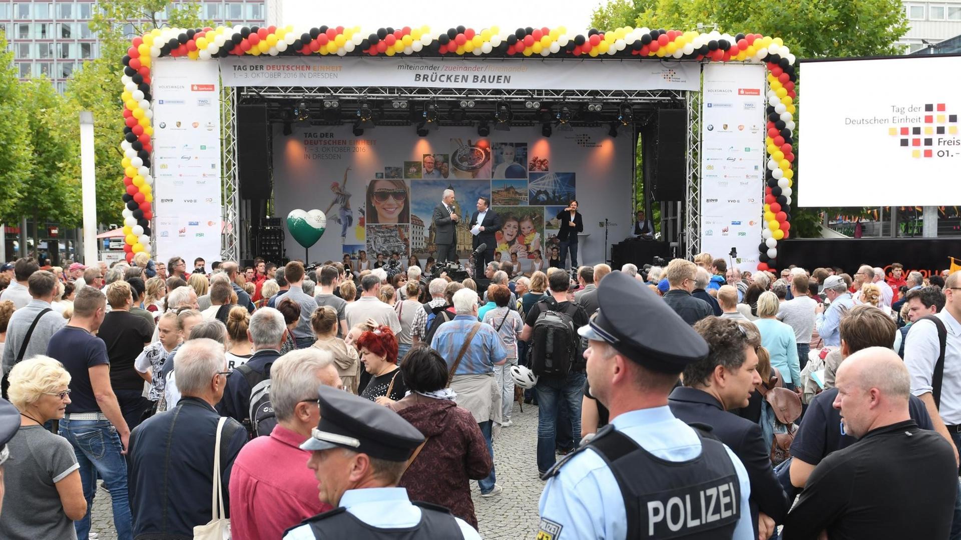 Sachsens Ministerpräsident Stanislaw Tillich steht zur Eröffnung des Bürgerfestes in Dresden auf einer Bühne. Im Publikum davor befinden sich auch zwei Polizei-Beamte.