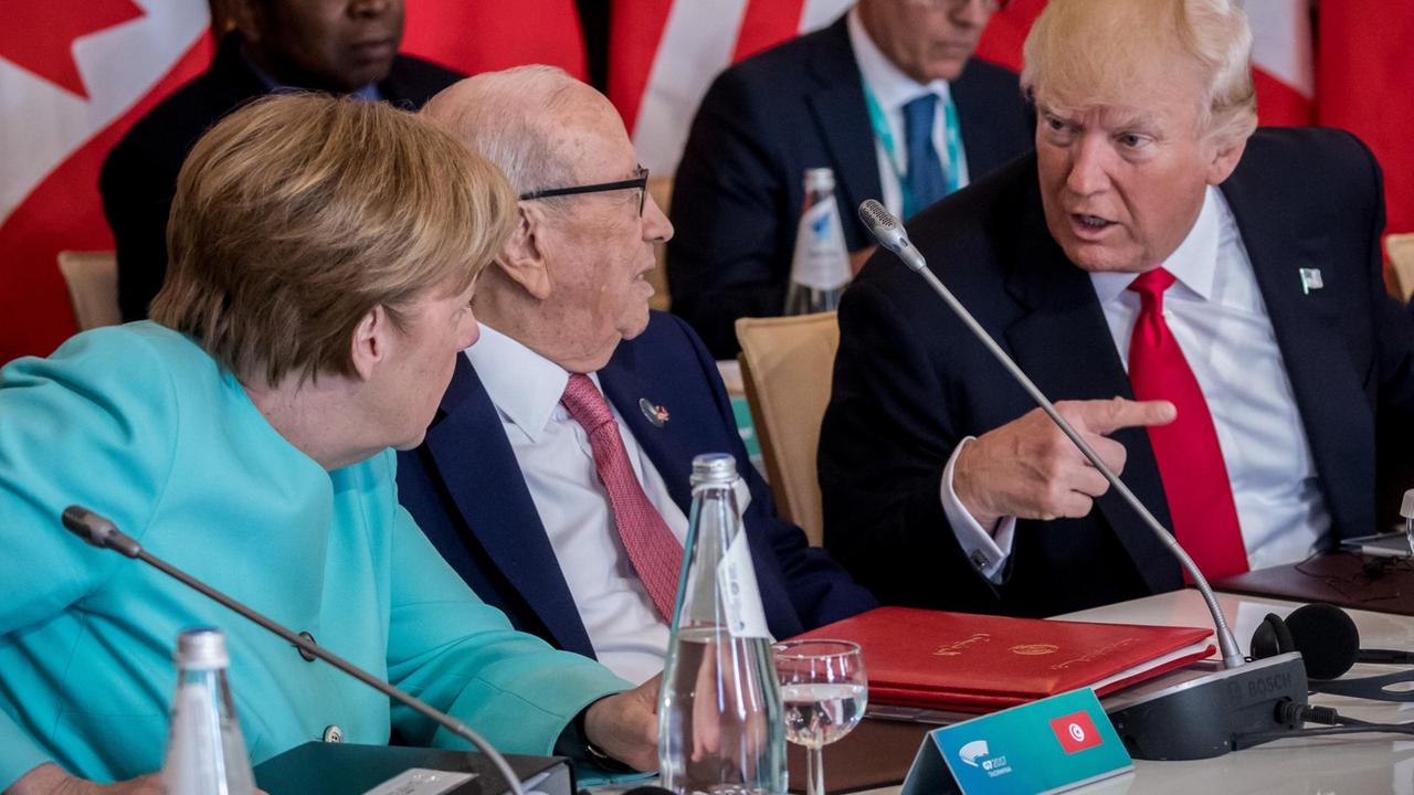 Bundeskanzlerin Angela Merkel (CDU) spricht am 27.05.2017 mit US-Präsident Donald Trump zu Beginn der Arbeitssitzung der G7 Staaten mit den Outreach Partnern in Taormina auf Sizilien, zwischen ihnen sitzt Tunesiens Präsident Beji Caid Essebsi. 