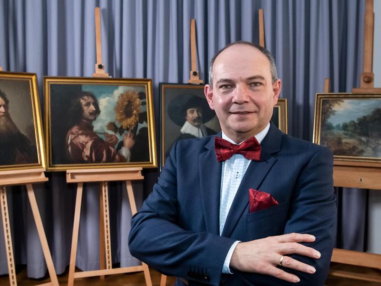 Der Bürgermeister von Gotha, Knut Kreuch, steht mit vor der Brust verschränkten Armen vor fünf vormals vermissten Gemälden.